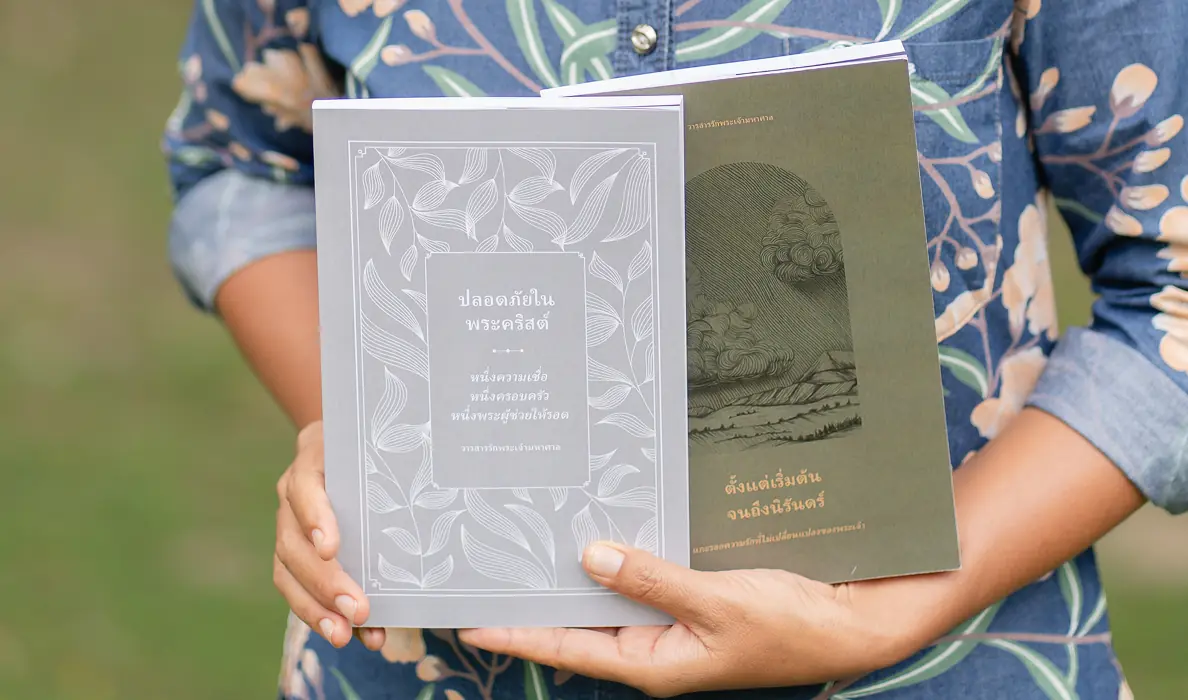 Kib holding two Thai-language Love God Greatly Bible studies